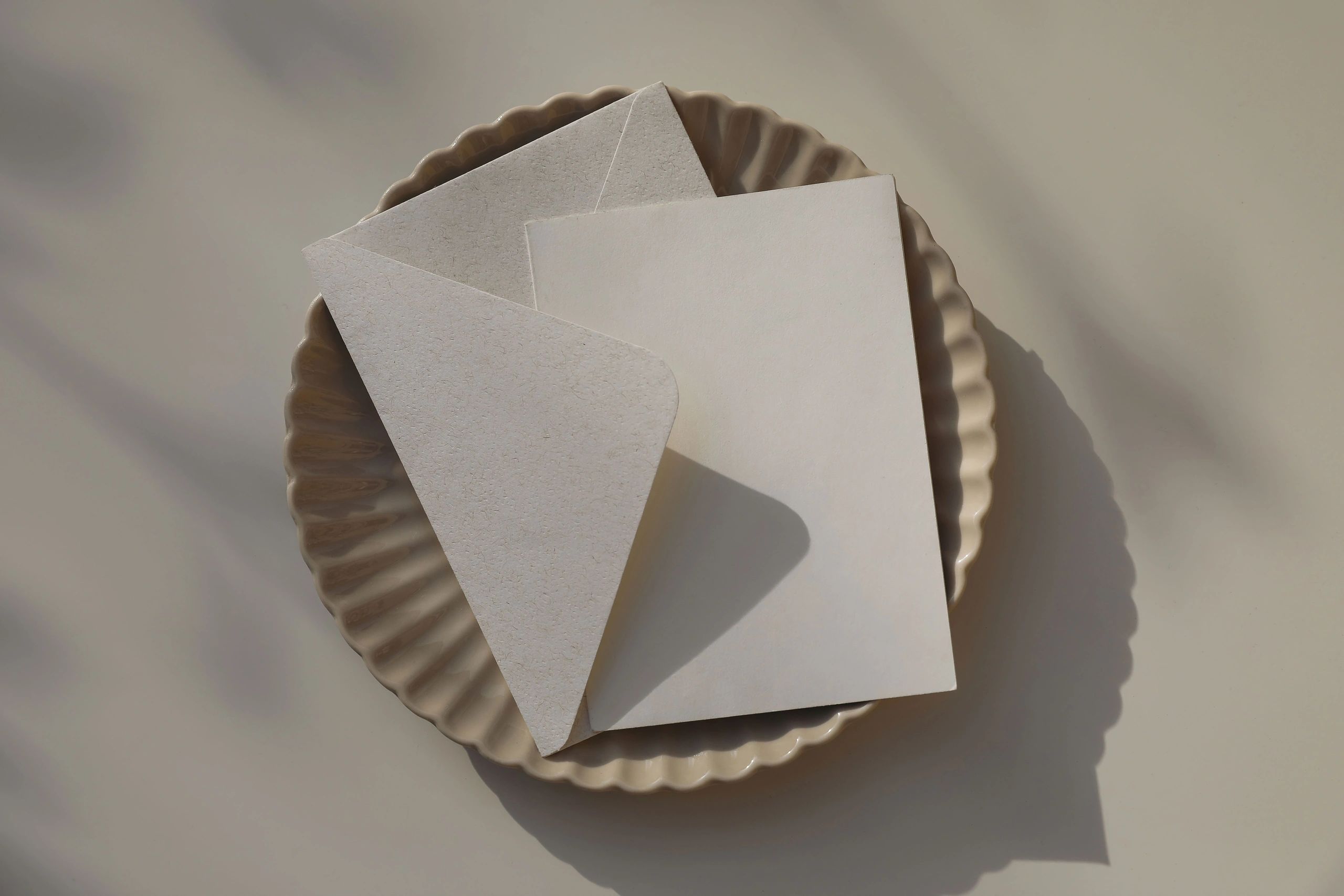 Neutral stationery flat lay with blank card and envelope in soft sunlightโrefined, giftable presentation.